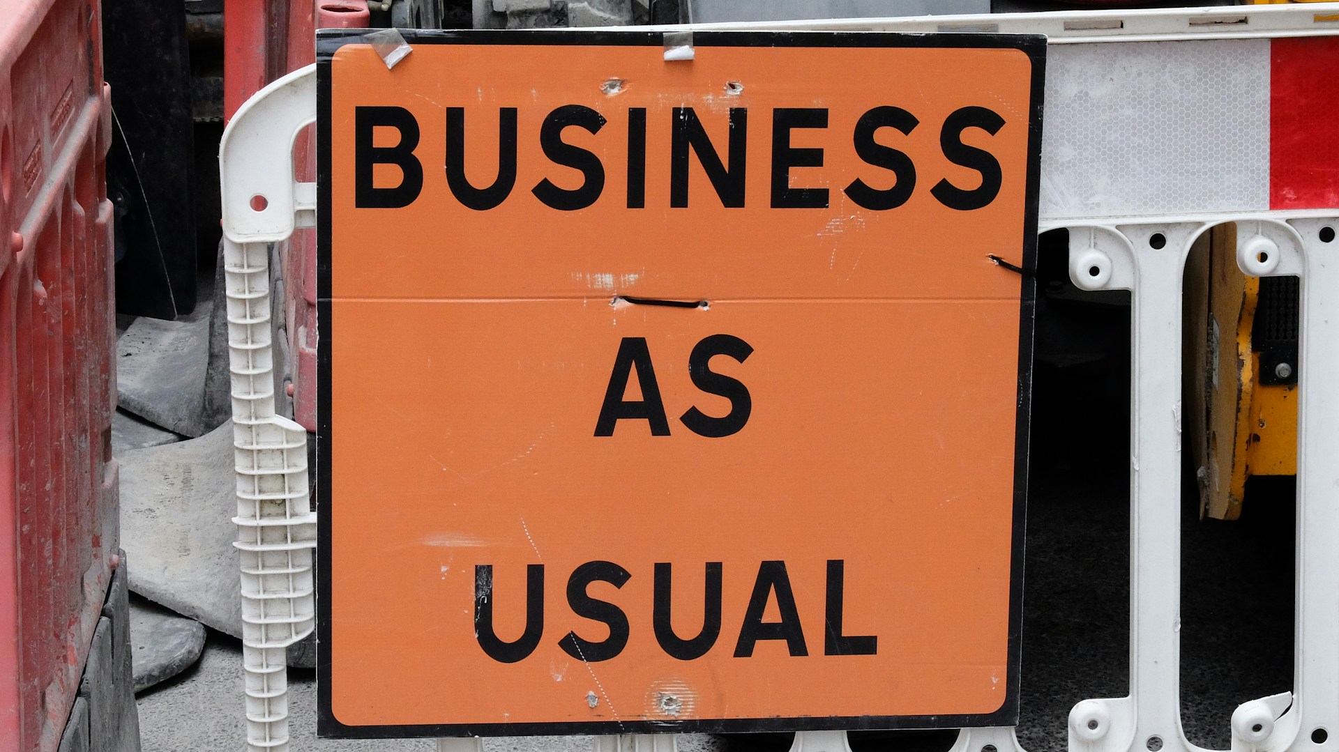 An orange sign saying 'business as usual'