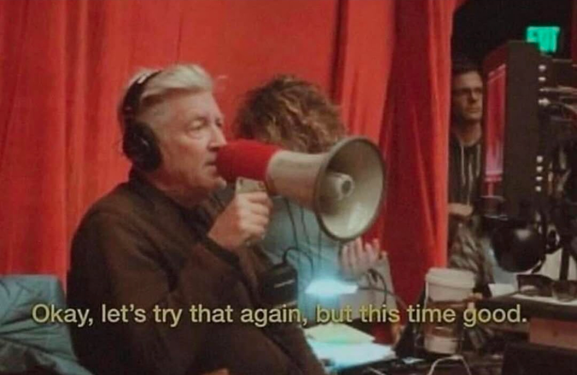 Person wearing headphones and speaking into a megaphone saying 'Okay, let's try that again, but this time good'